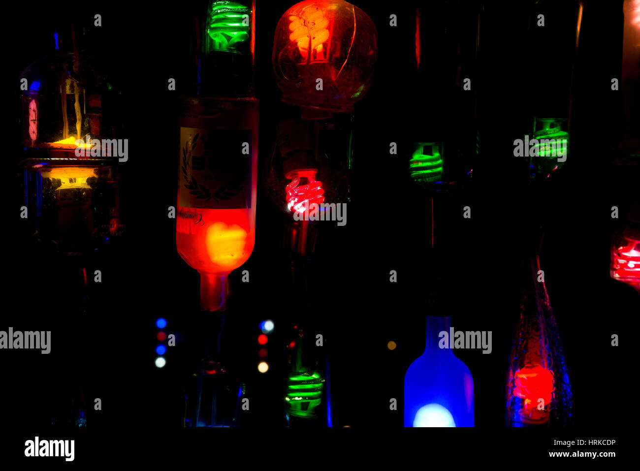 Flasche Lichter in der Nacht. Farbige Glühbirnen in alten Alkoholflaschen. Stockfoto