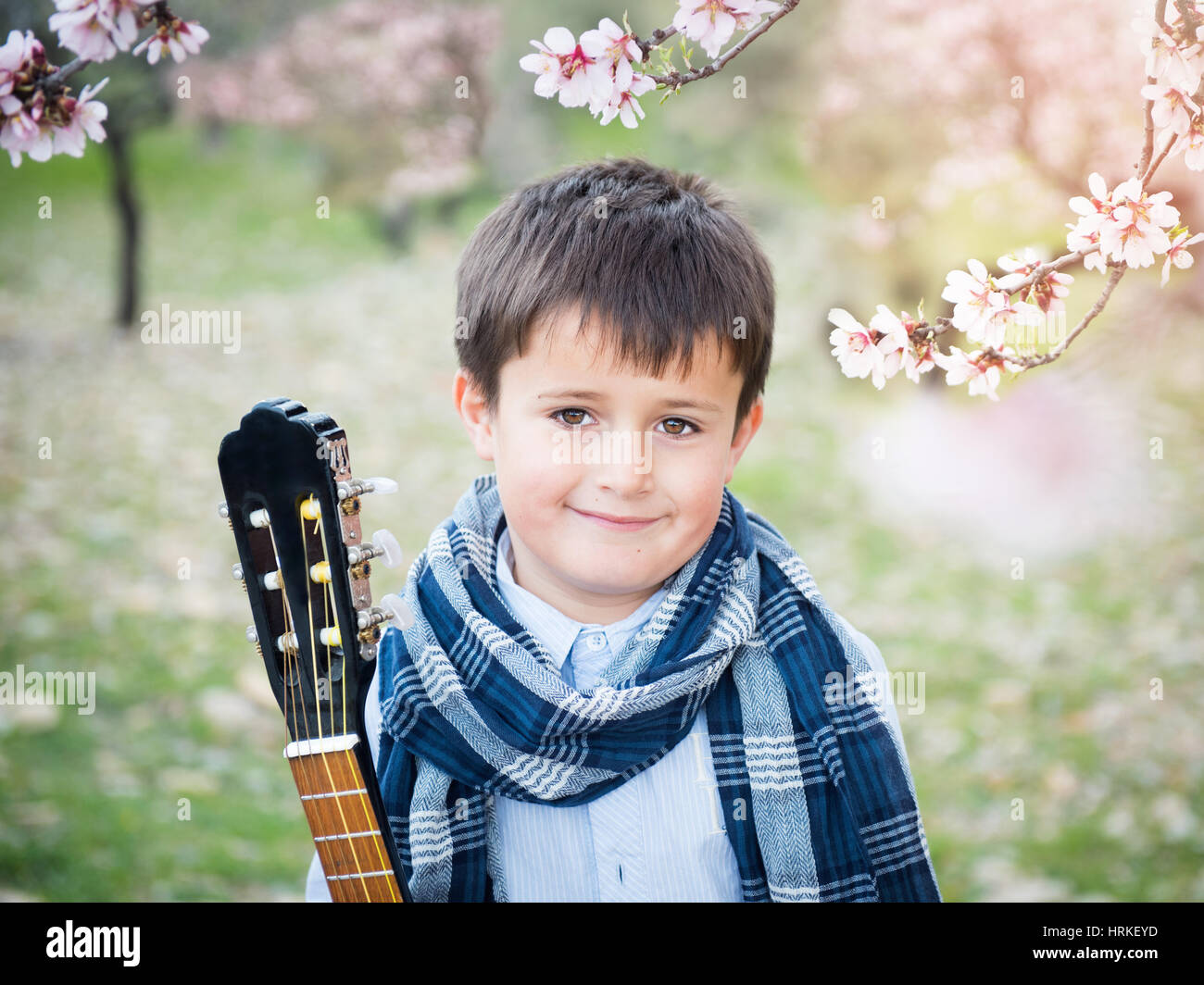 Hübscher Junge in blühenden Gärten mit einer Gitarre Stockfoto
