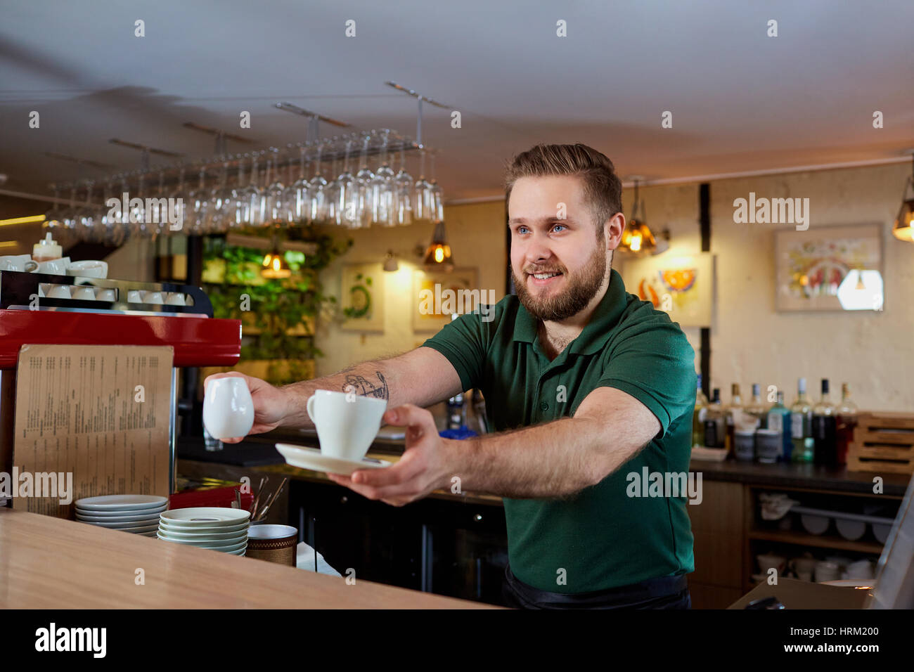 Barista mit Kaffeetasse in der Hand hinter Bar. Stockfoto