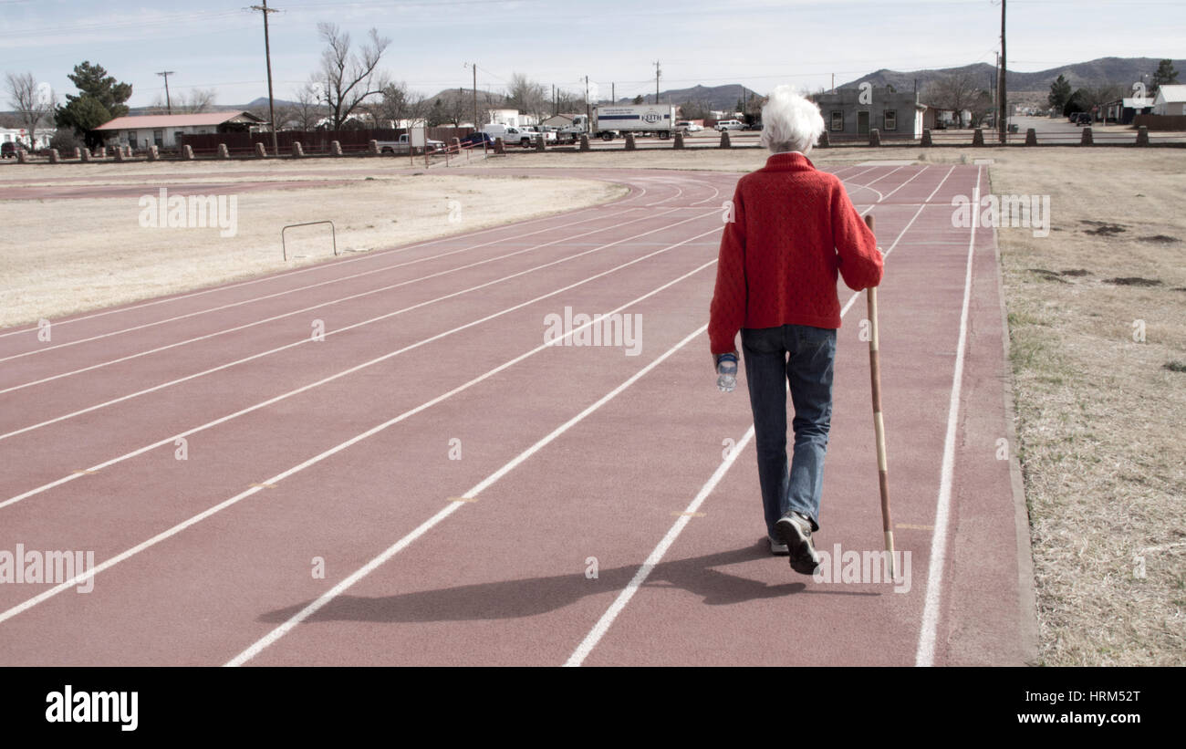 Ältere Frau zu Fuß auf einem Leichtathletik-Stadion Stockfoto