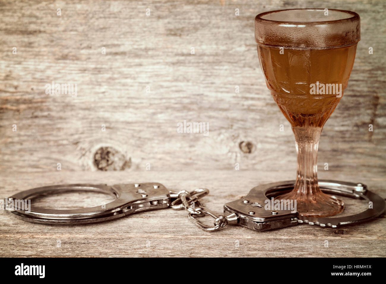 Glas Alkohol mit Handschellen als Symbol für Alkoholmissbrauch Stockfoto
