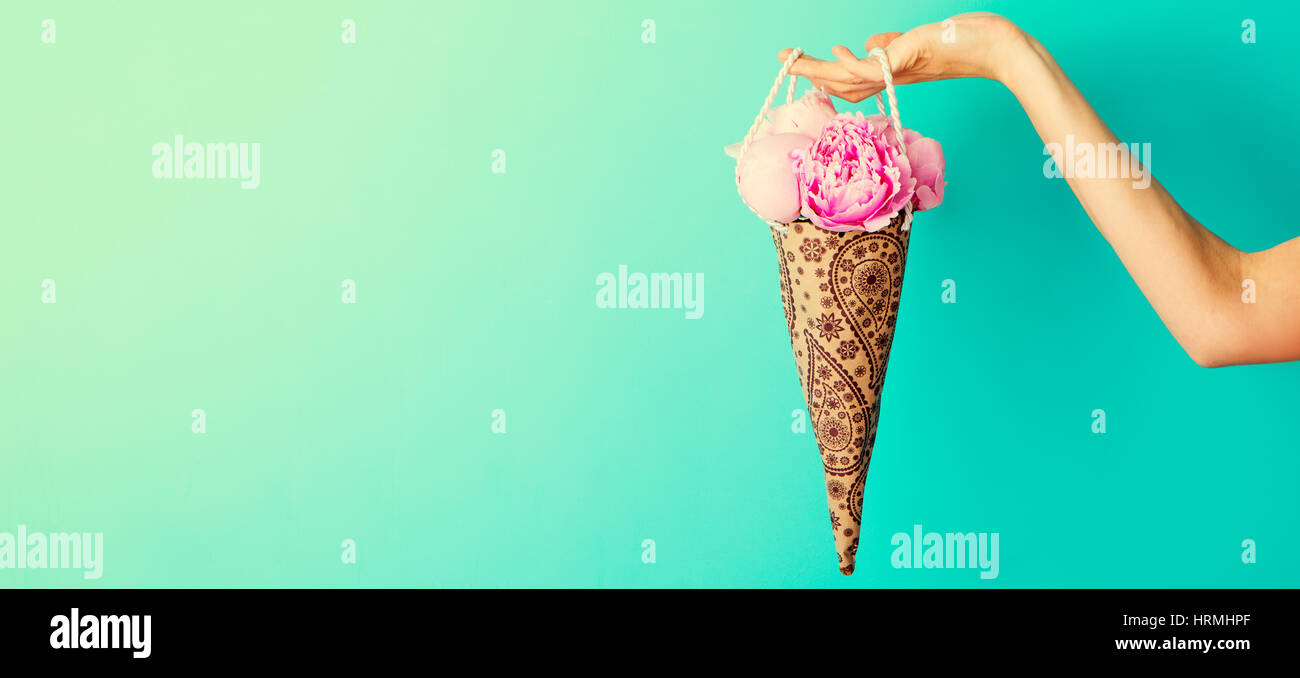 Blumenstrauß in weiblicher Hand auf eine türkisfarbene Wand Hintergrund Pfingstrosen. Textfreiraum Stockfoto