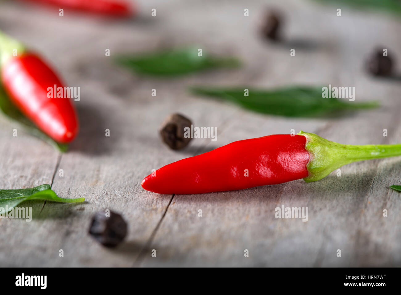 Rote heiße Chilis auf hölzernen Hintergrund mit Kräutern Stockfoto