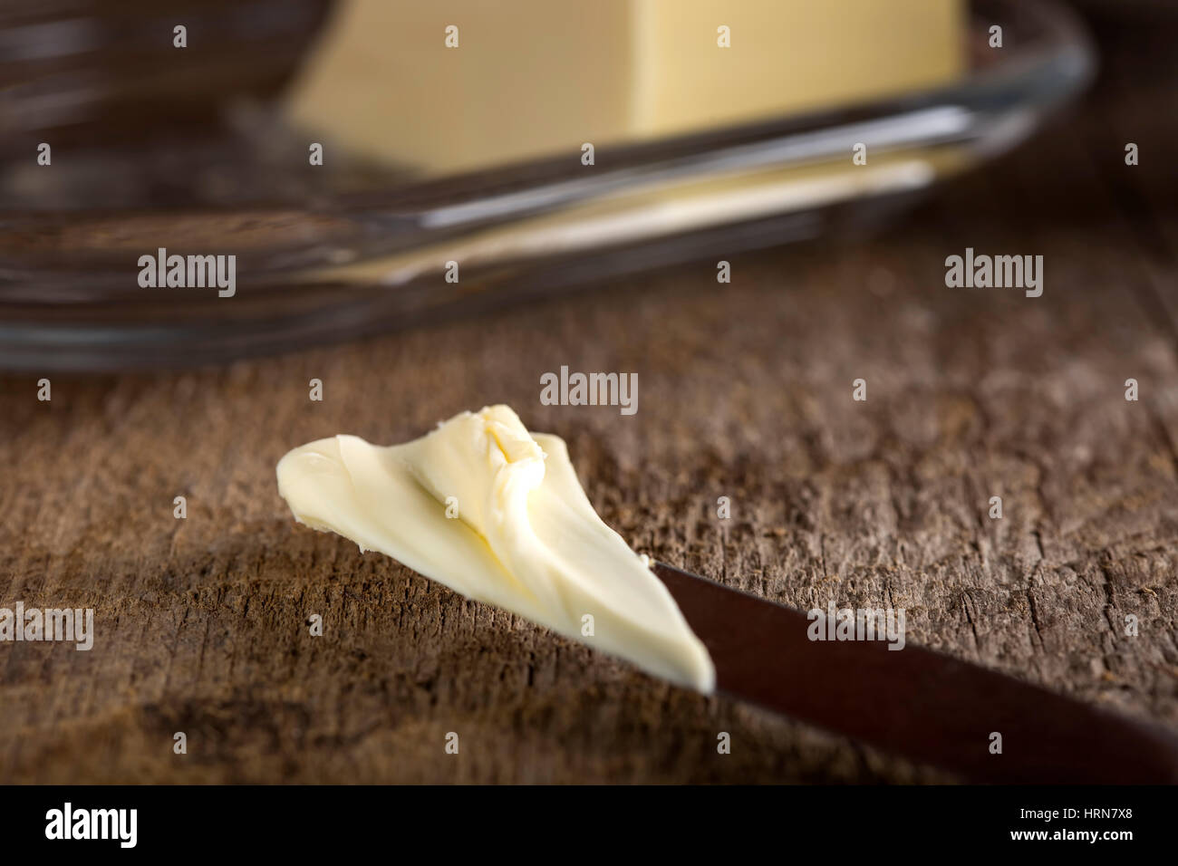 Nahaufnahme von Butter auf Küchenmesser auf hölzernen Hintergrund Stockfoto