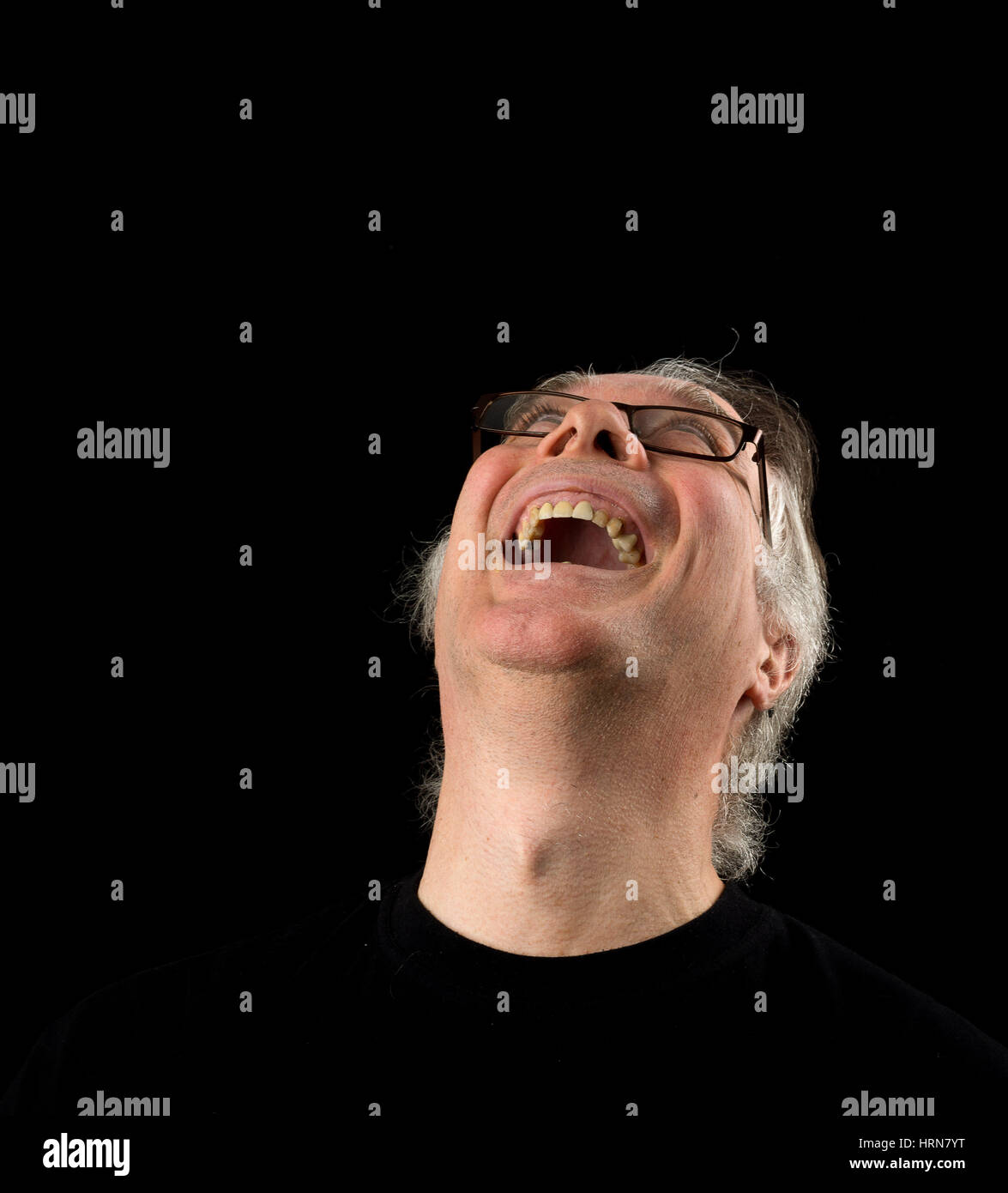 Kopfschuss Porträt eines älteren Mannes in seinen 50ern hautnah. Männchen tragen schwarzes T-shirt und auf schwarzem Hintergrund isoliert. Stockfoto