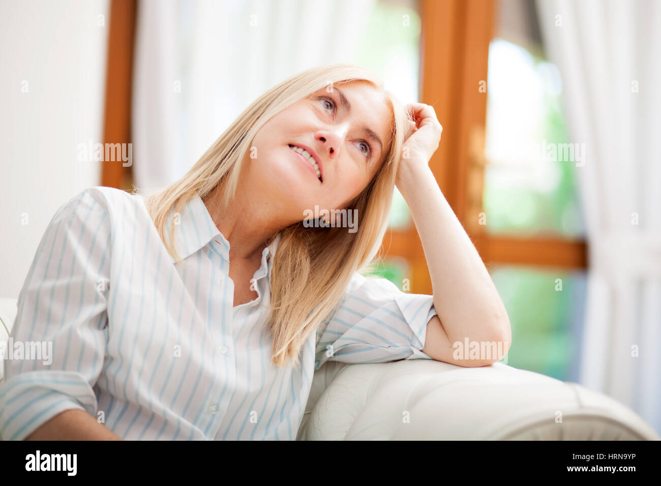 Senior Woman Relaxing On Sofa zu Hause Stockfoto
