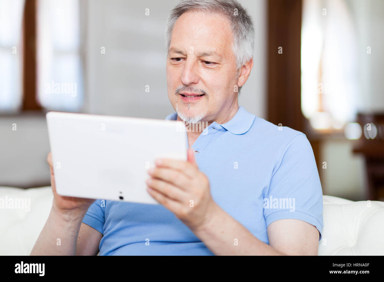 Reifer Mann in Sofa-Surfen mit tablet Stockfoto