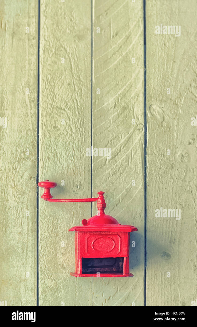 Rote alte mechanische Kaffeemühle auf weißer Holztisch.  Vertikale Jahrgang farbigen Hintergrund Stockfoto