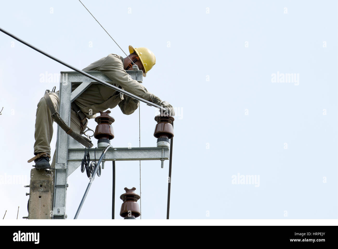 Elektriker Lineman auf Arbeit auf elektrische Post Elektromasten klettern. Stockfoto