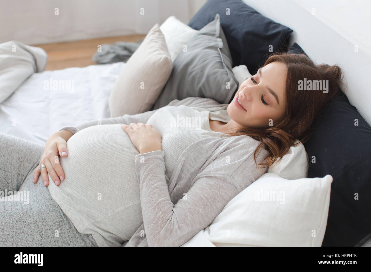 Schwangere smiling brunette Frau liegend auf Bett Stockfoto