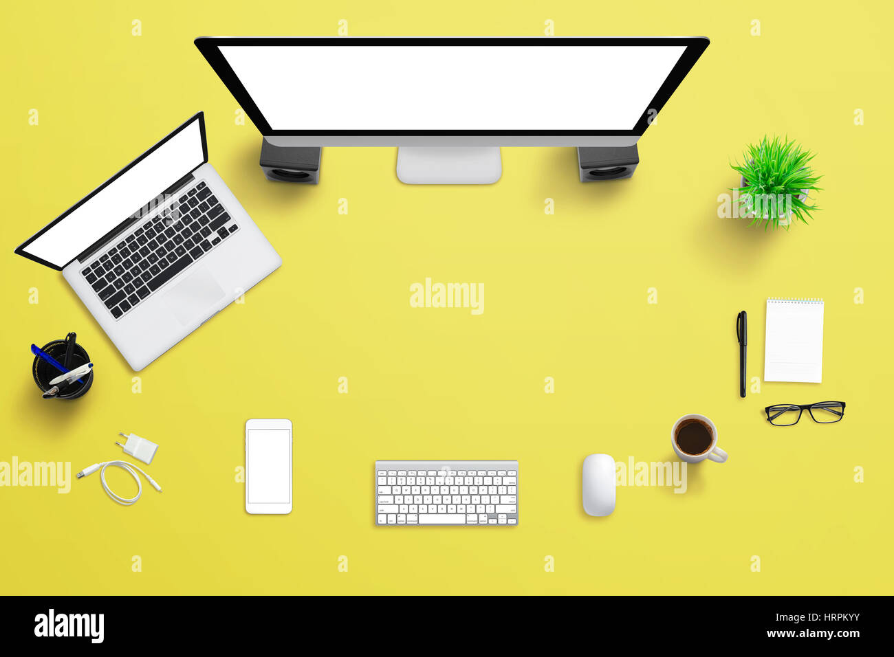 Gelbe Schreibtisch mit Computer-Display, Laptop und Handy. Kreative Szene mit freiem Speicherplatz für Text. Stockfoto