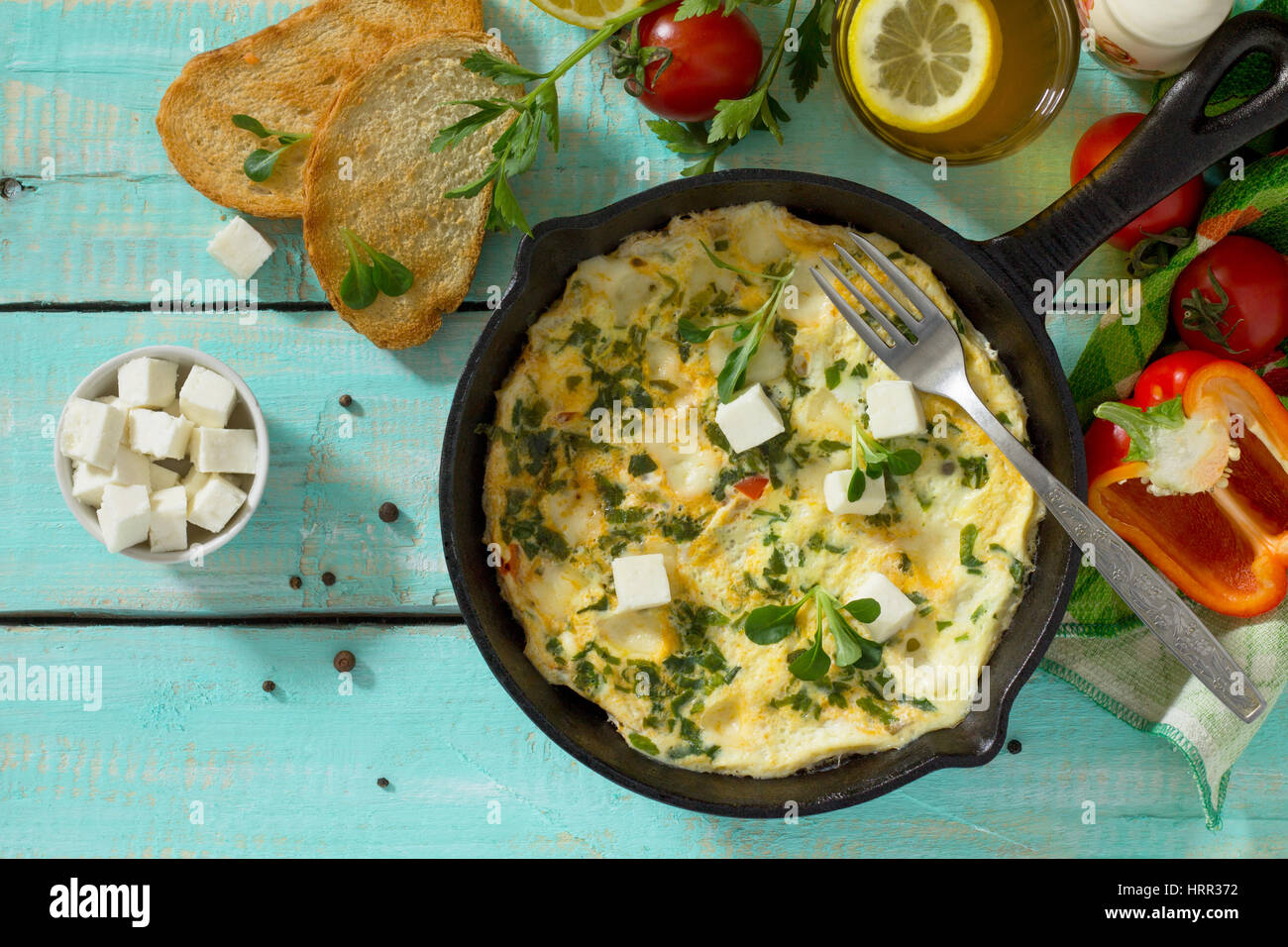 Omelett mit Paprika, Tomaten und Feta-Käse in einer gusseisernen Pfanne auf einem Holztisch. Das Konzept der gesunden Ernährung und Diät. Bulgarische cuis Stockfoto