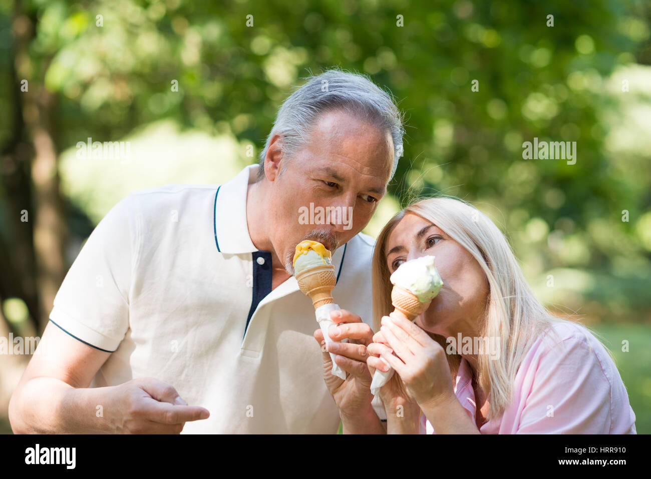 Porträt einer glücklich älteres paar Essen eine schmelzende Eis in einem park Stockfoto
