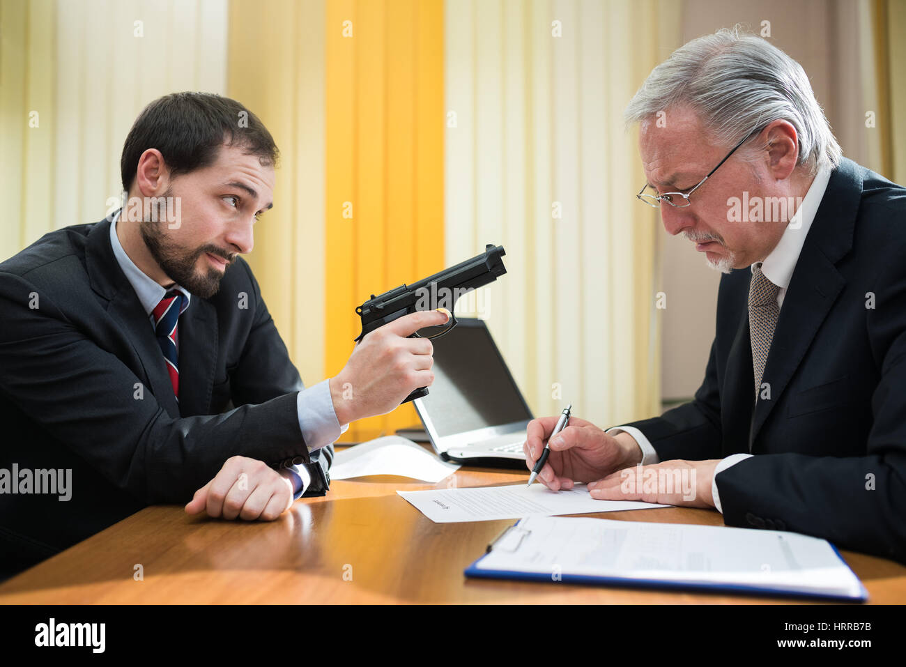 Kriminelle zwingen einen Geschäftsmann einen Vertrag unterschreiben Stockfoto