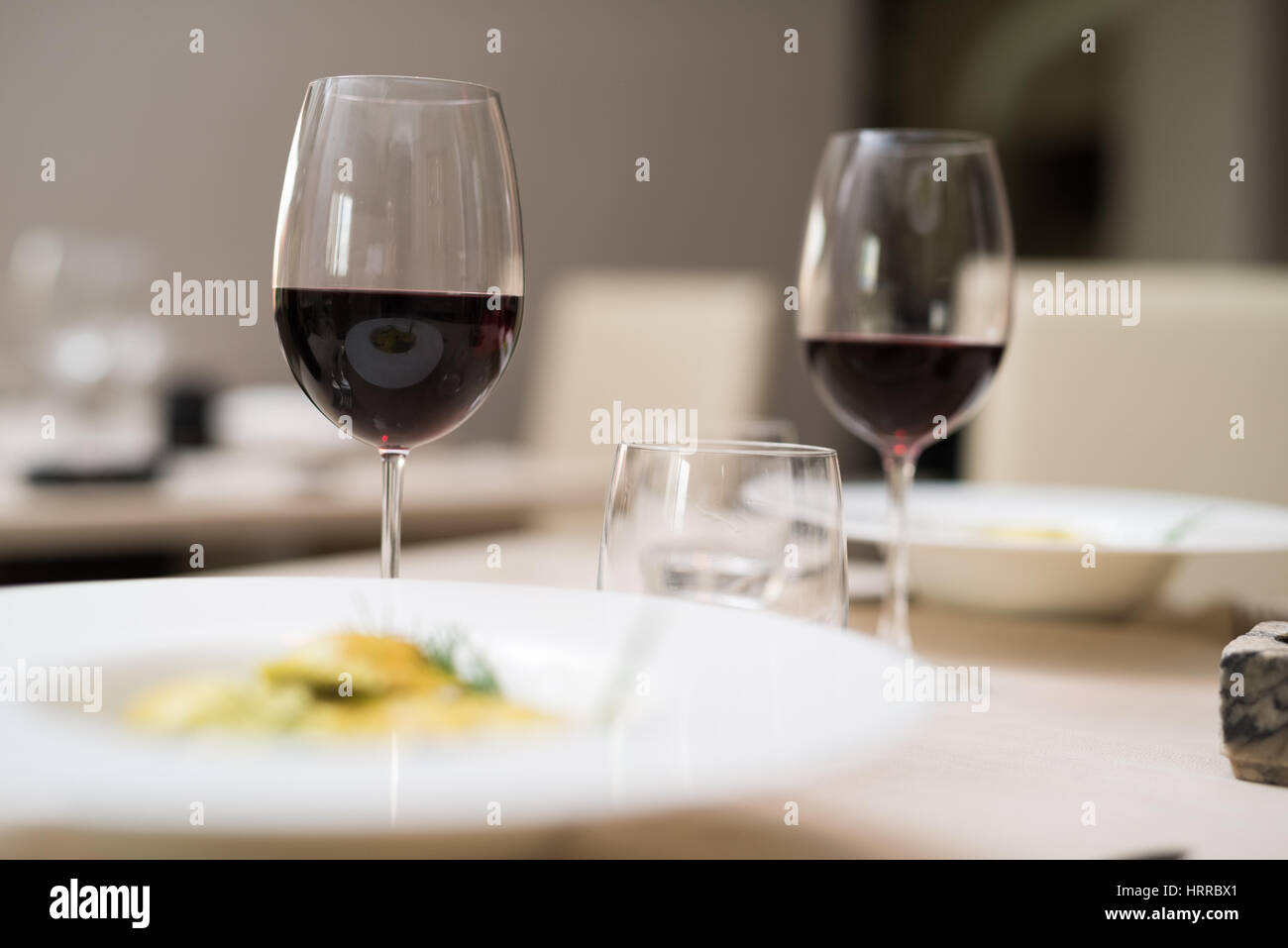 Tisch im Restaurant ohne Menschen. Sehr geringe Schärfentiefe, Fokus auf dem Glas auf der linken Seite. Stockfoto