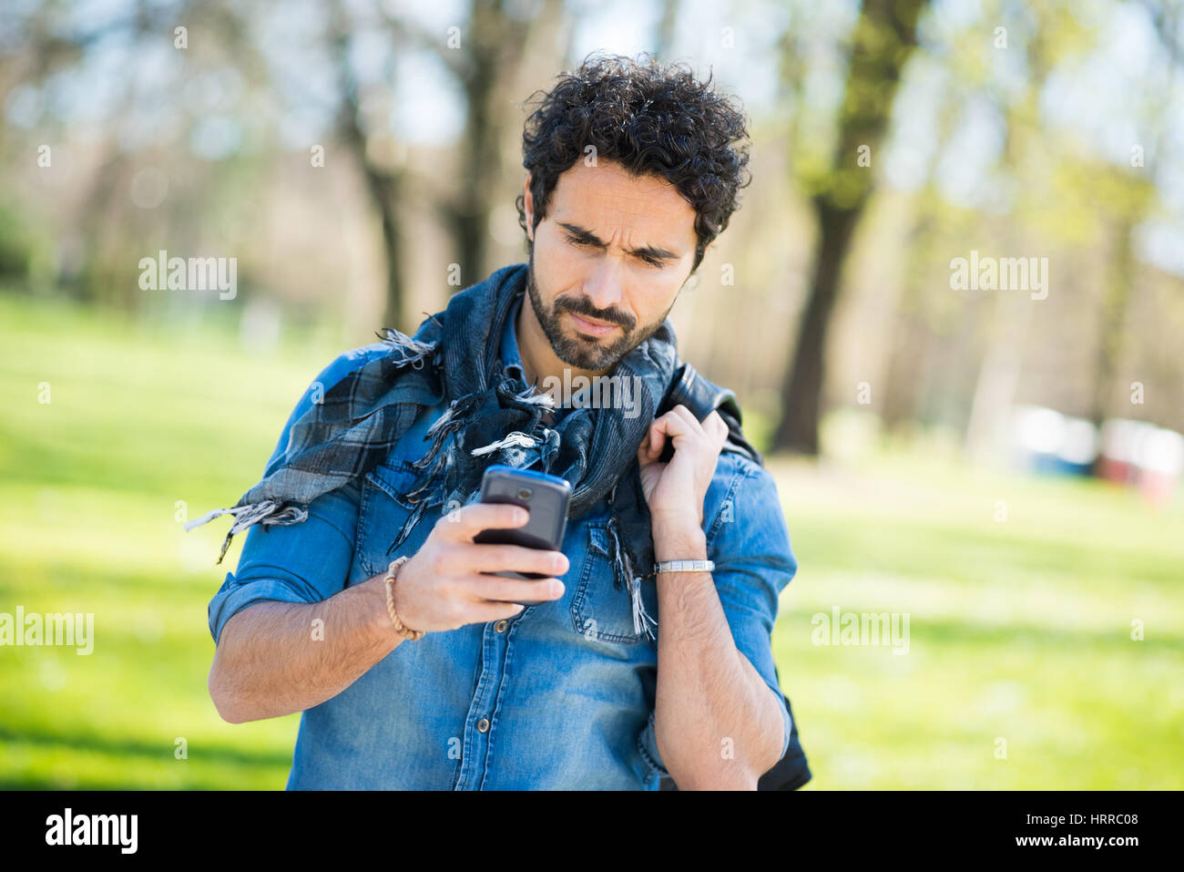 Mann zu Fuß beim Betrachten seines Mobiltelefons Stockfoto