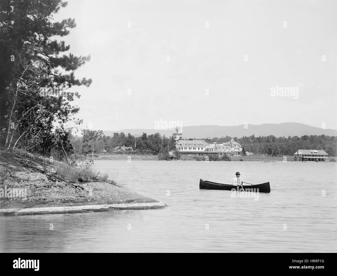 Mann im Kanu mit Saranac Inn im Hintergrund, oberen Saranac Lake, New York, USA, William Henry Jackson für Detroit Verlag, 1902 Stockfoto
