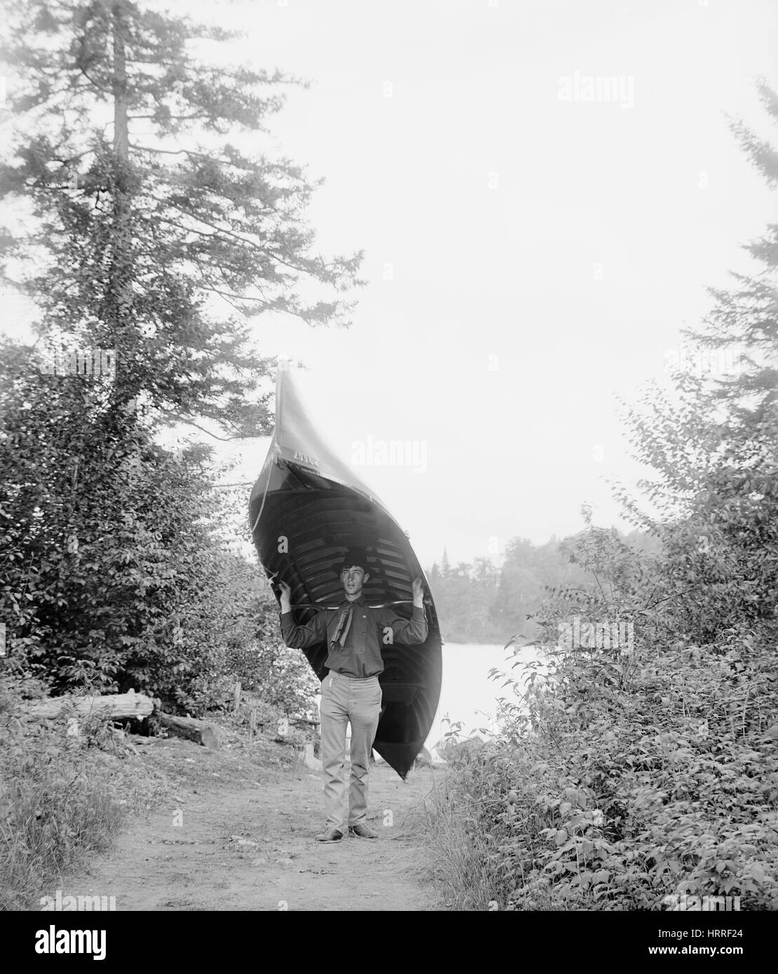 Mann trägt Kanu vom See, Adirondack Mountains, New York, USA, William Henry Jackson für Detroit Verlag, 1902 Stockfoto