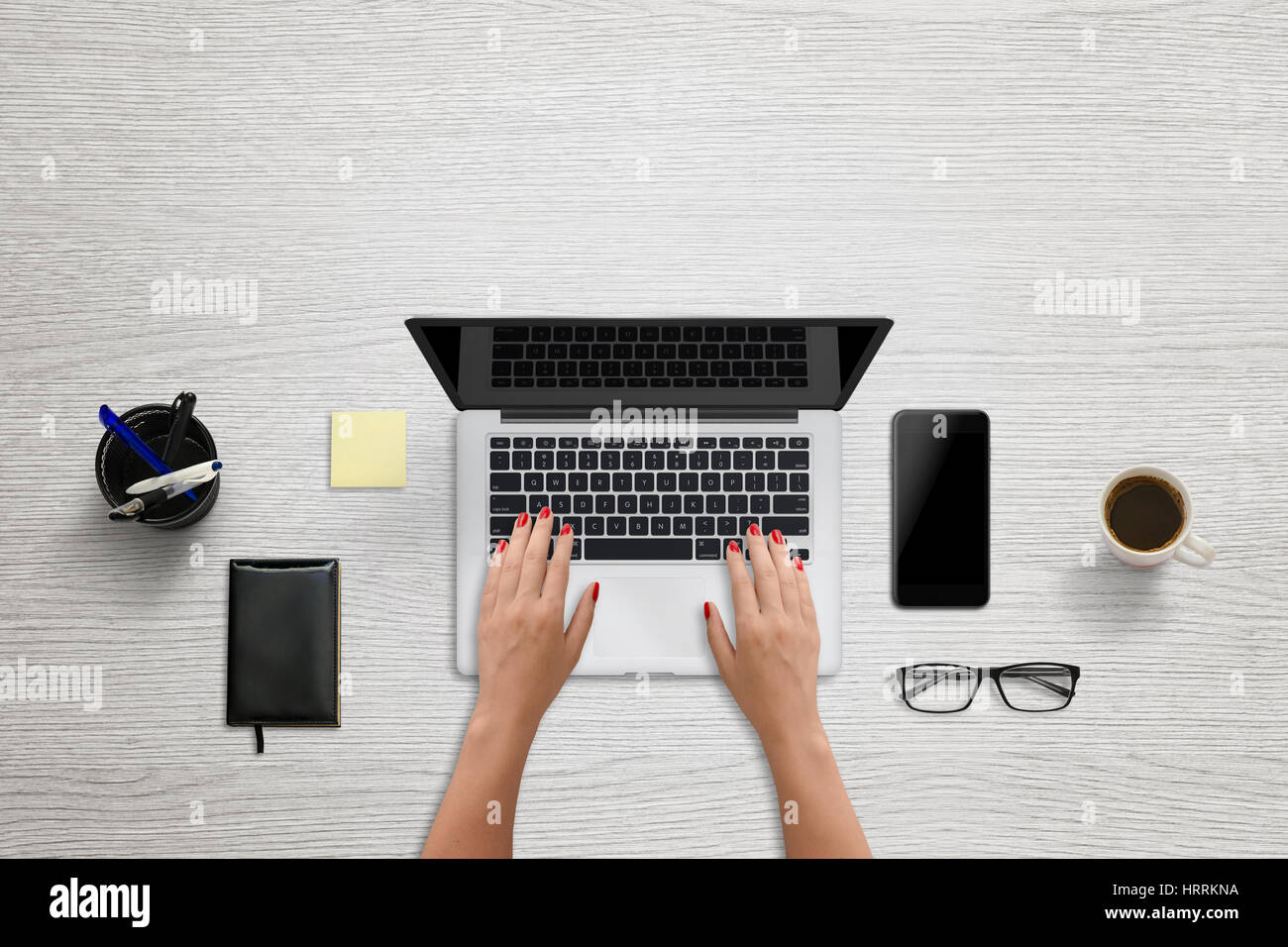 Frau Hahn auf Laptop-Tastatur. Leerer Bildschirm für Mockup, Design-Präsentation. Modernes Büro mit Schwarz Smartphone neben Szene. Pad, Kaffee, Gläser, p Stockfoto