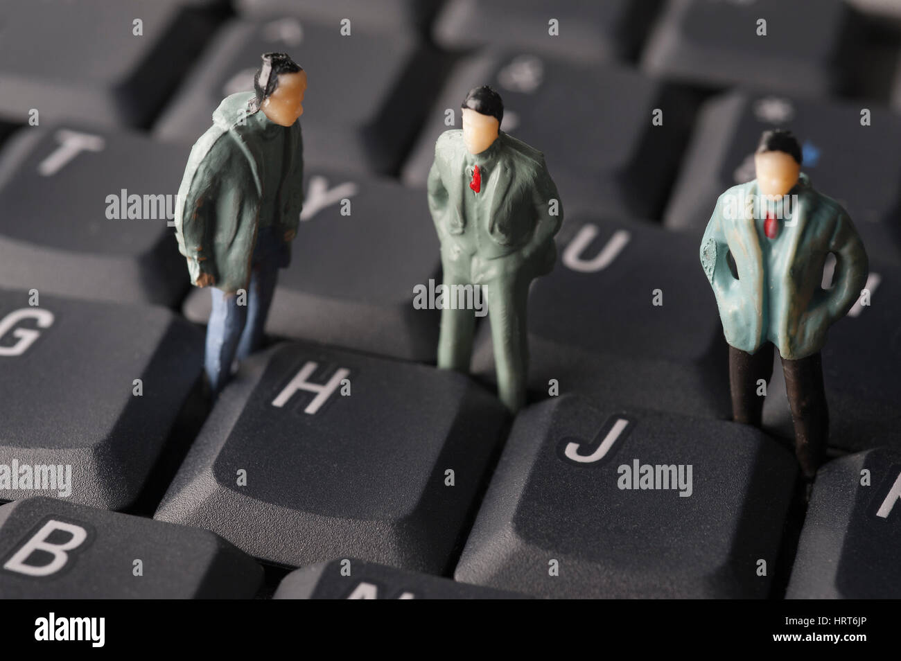 Männliche Figuren stehend auf Computer-Tastatur Stockfoto