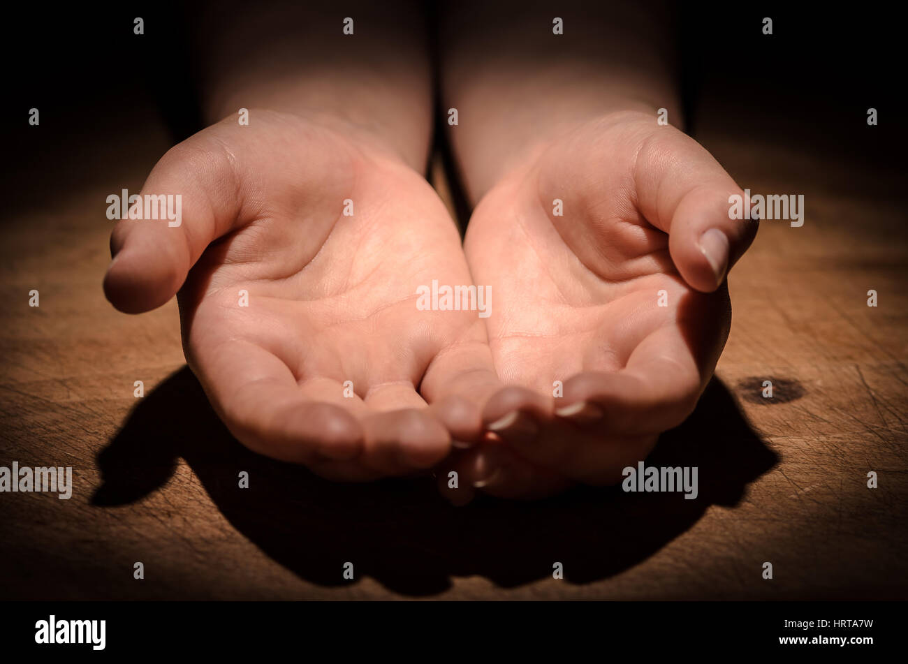 Offene Hände betteln um Hilfe auf dem Holztisch Stockfoto