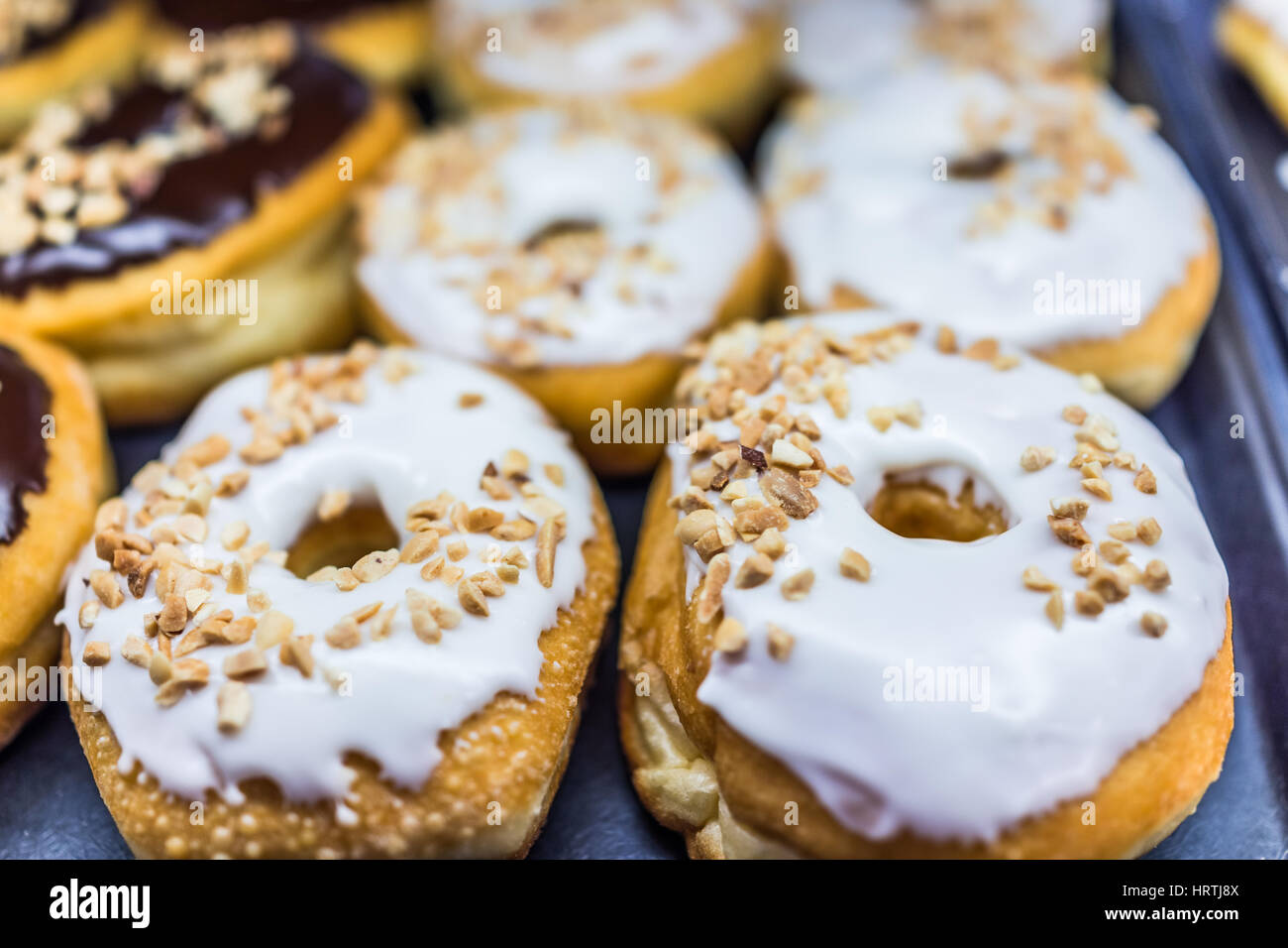 White iced Donuts mit gehackten Erdnüssen Stockfoto