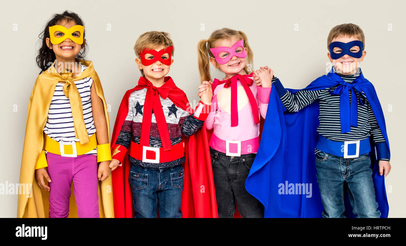 Kleine Kinder kleiden Superhelden an den Händen halten Stockfoto