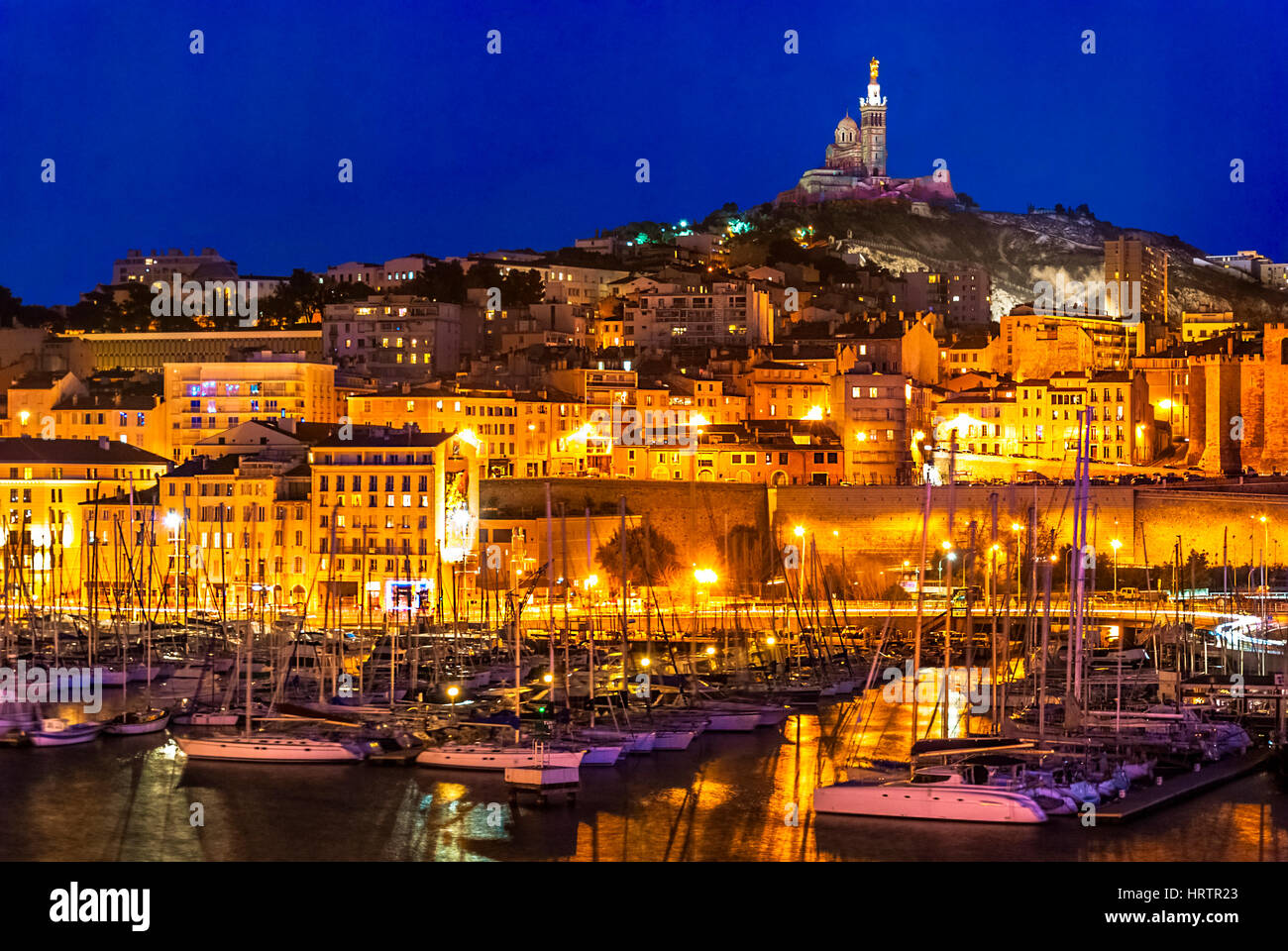 Der Hafen von Marseille in der Nacht. Blick in Richtung der Kathedrale de Notre-Dame-de-la-Garde hoch auf einem Hügel mit Blick auf die Stadt. Cote d ' Azur in der Sout Stockfoto