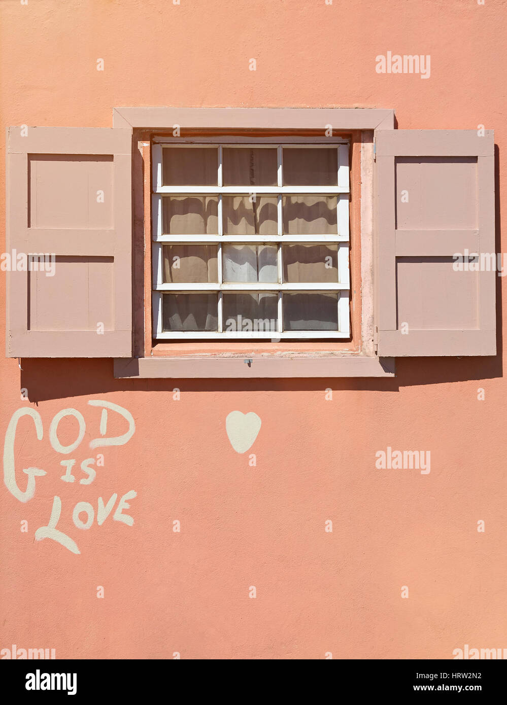 Holzfenster in rosa Hauswand mit Graffiti-Gott ist Liebe. Einfaches Holz Fenster Stockfoto