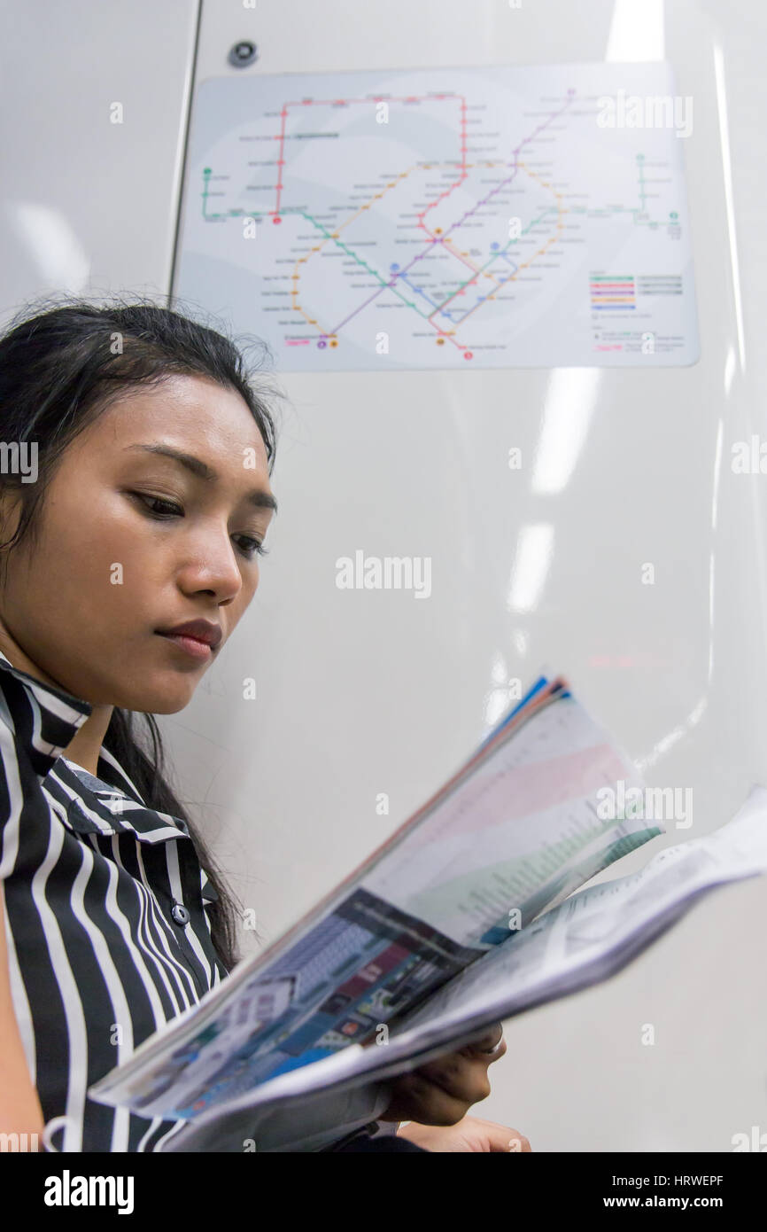 Asiatische Touristen sieht sich die Karten in der u-Bahn. Eine Frau liest Plan für städtischen Nahverkehr. Mädchen geht mit dem Zug und Studium Karten mit Noten. Stockfoto