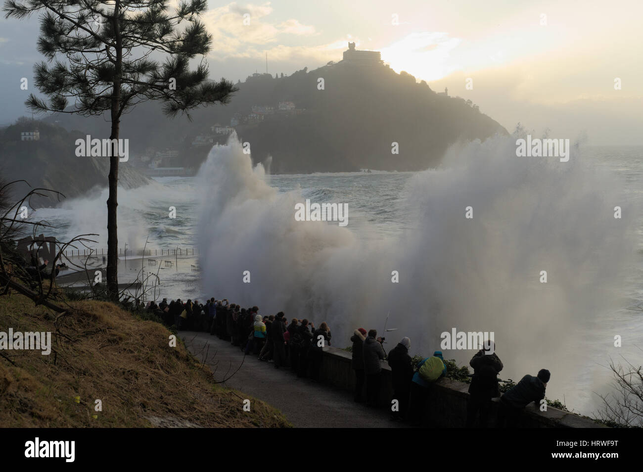 Einige Leute genießen Sie die Wellen brechen sich an der Küste in San Sebastian, Spanien. Stockfoto