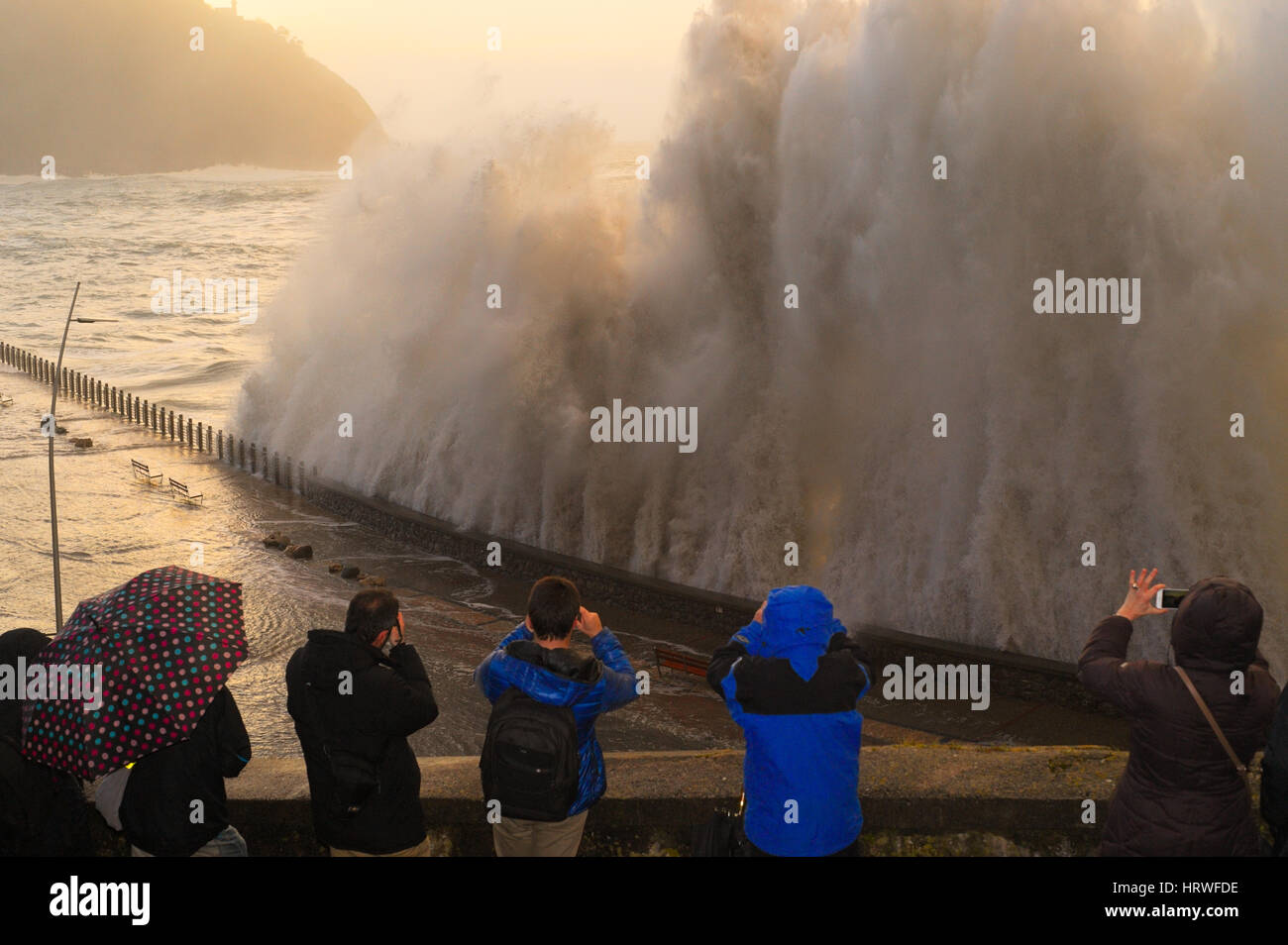 Einige Leute genießen Sie die Wellen brechen sich an der Küste in San Sebastian, Spanien. Stockfoto