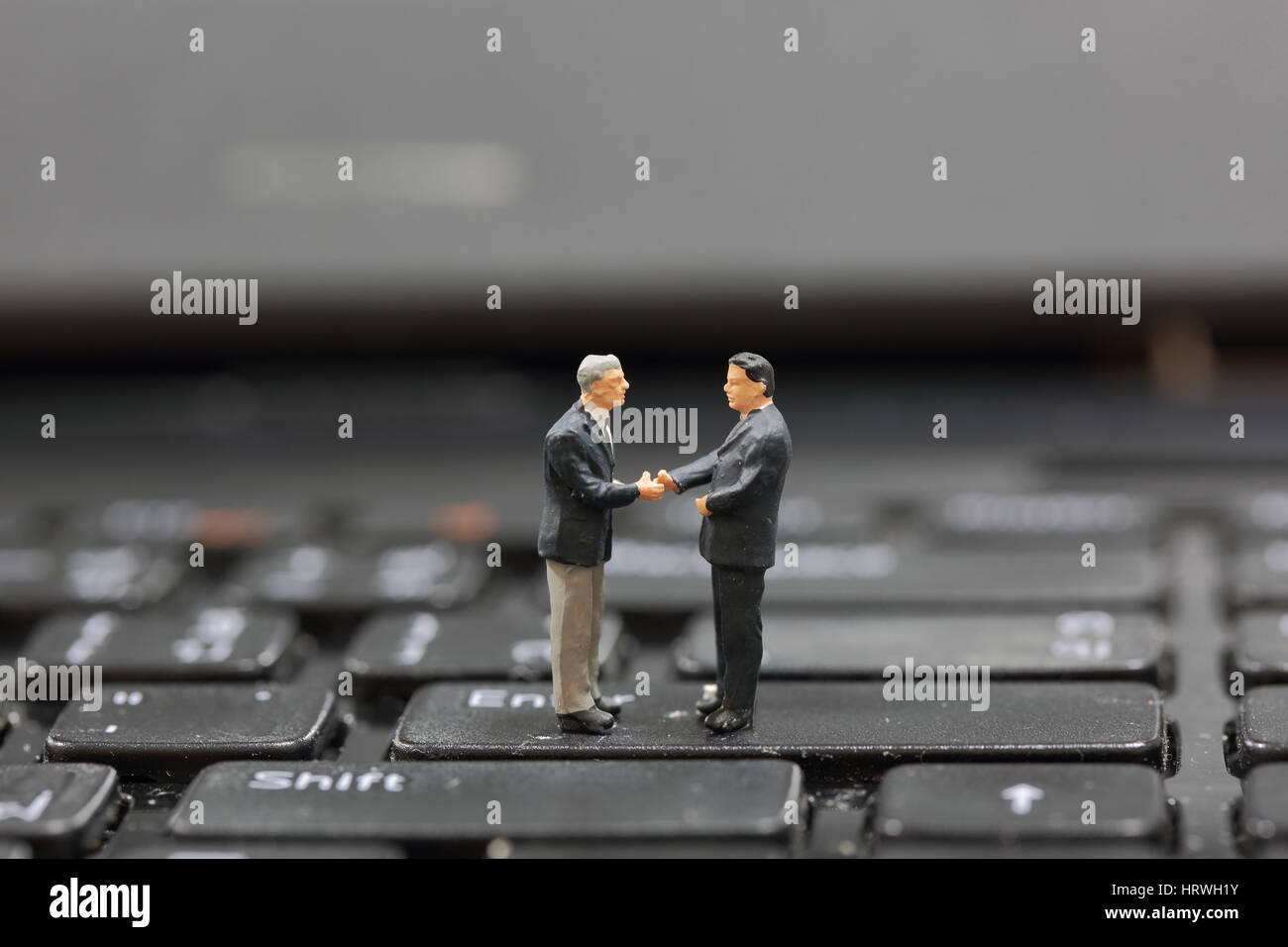 Selektiven Fokus Miniatur Geschäftsmann Handshake auf die Schaltfläche Enter Taste Tastatur Hintergrund als Verpflichtung Konzept. Stockfoto