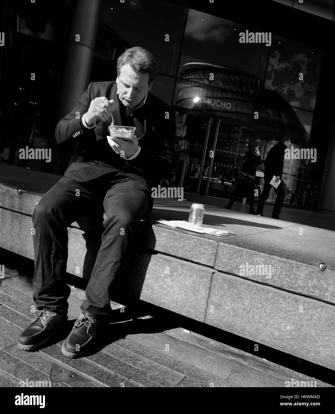 Ein Mann isst sein Mittagessen auf seine Mittagspause in More London Stockfoto