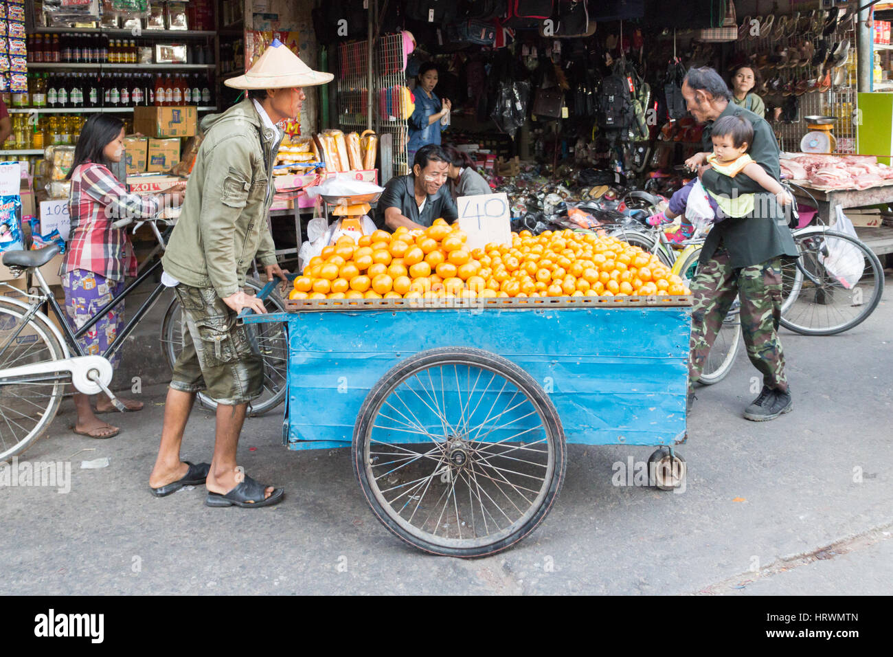 Anbieter drängen seiner Wagen voller Orangen durch die Straßen von Mae Sot, Thailand Stockfoto