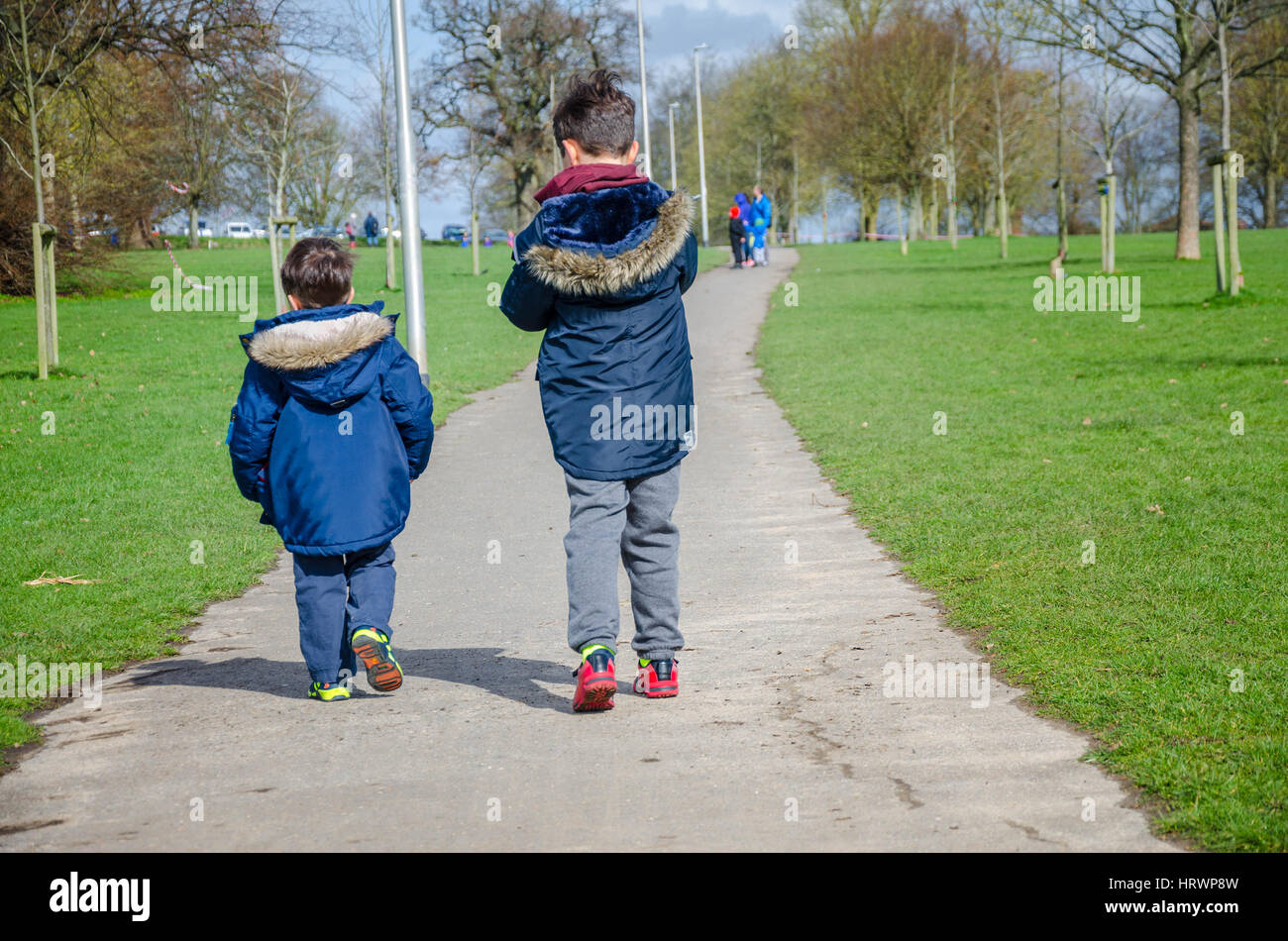 Zwei junge Brüder, gesehene Form hinter, zu Fuß entlang einem Pfad im Prospect Park in Reading, UK. Stockfoto