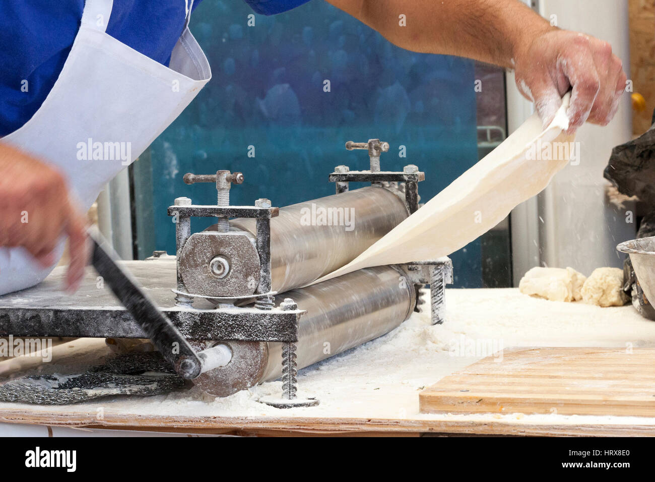 Männer Händen ausrollen Teig hautnah. Mann, Teig vorbereiten, Kochen von Teigwaren auf einem Holztisch im café Stockfoto