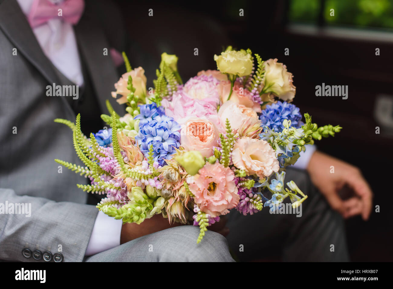 Schöne stilvolle Bräutigam mit Blumenstrauß in das Hochzeitsauto. Stockfoto