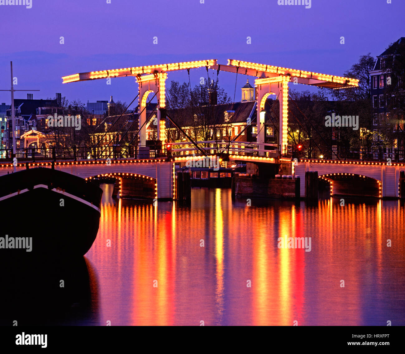 Skinny Bridge (Magere Brug) reflektiert in der Amstel bei Nacht, Amsterdam, Holland, Niederlande Stockfoto