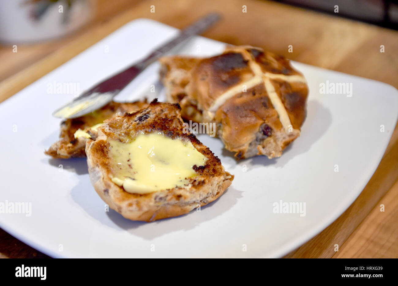 Gerösteten Hot Cross Brötchen mit Butter für Ostern Karfreitag feiern in UK Stockfoto