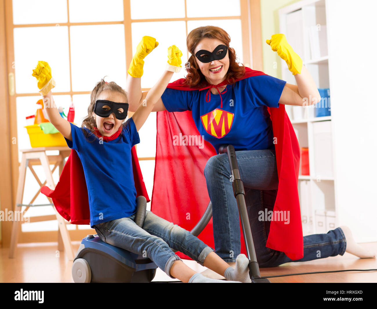 Starke Superhelden Hausfrau und Kind Tochter bereit, die Reinigung der Zimmer. Hausarbeit und Haushalt-Konzept. Stockfoto