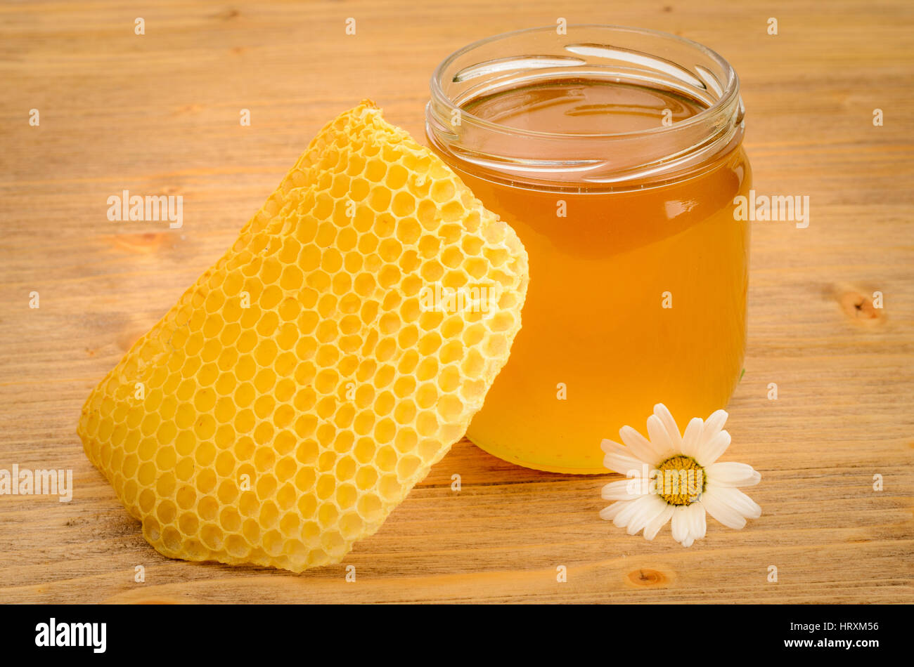 Glasglas voller Honig mit Waben auf einem Holztisch Stockfoto