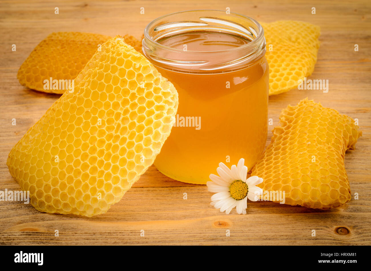 Glasglas voller Honig mit Waben auf einem Holztisch Stockfoto