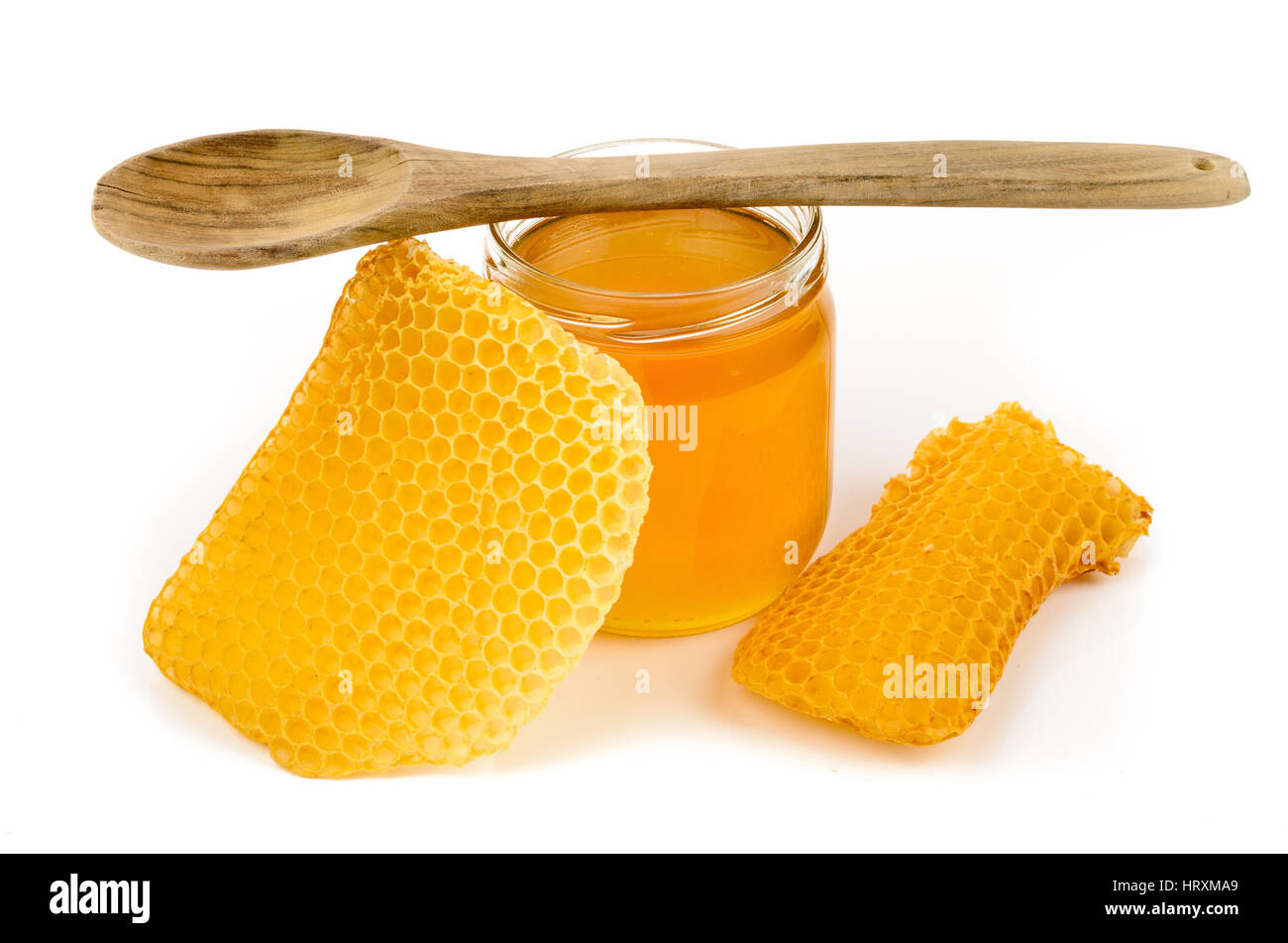 Glas voller Honig mit Waben und Kochlöffel auf weißem Hintergrund Stockfoto