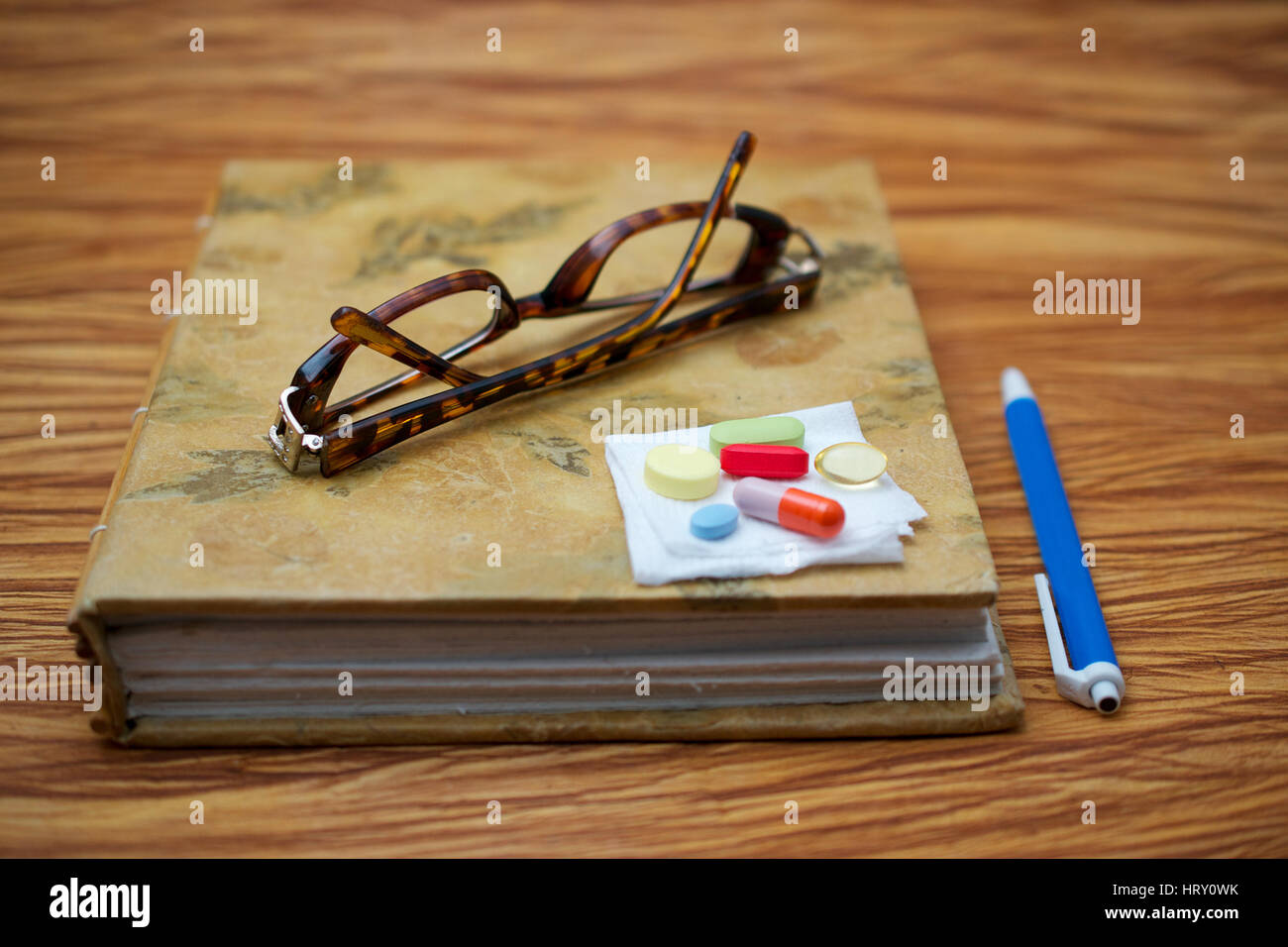Ein paar gebrochene Leser Gläser auf geschlossenen Journal und einen Stift auf Holztisch, was auf eine ältere Person eine Pause, um Medikamente zu nehmen Stockfoto