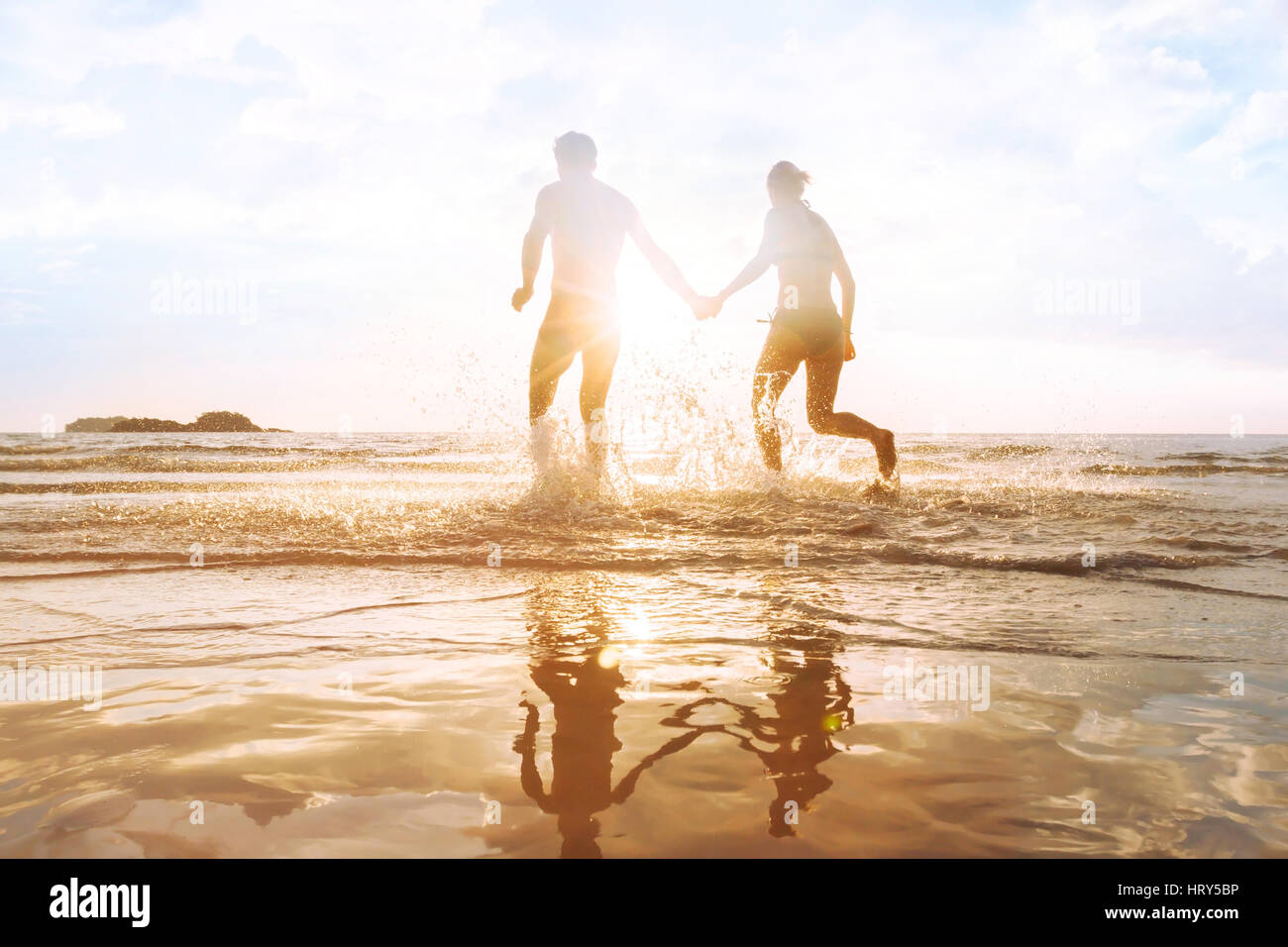 glückliche junge Paare, die Spaß am Strand bei Sonnenuntergang, Spritzwasser, das Leben genießen Stockfoto
