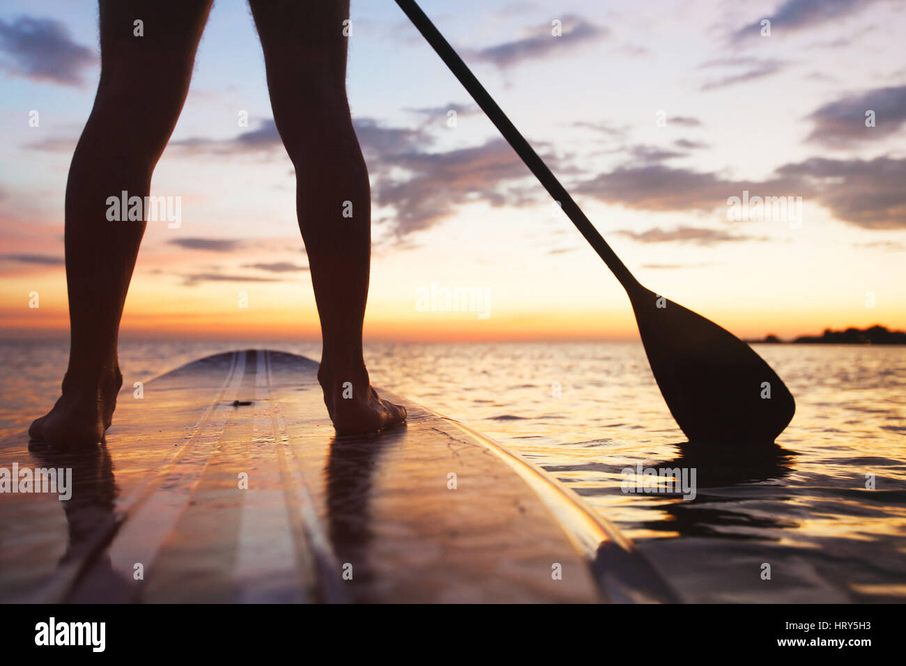 Paddle Board am Strand, Nahaufnahme von stehenden Beine und Paddel Stockfoto