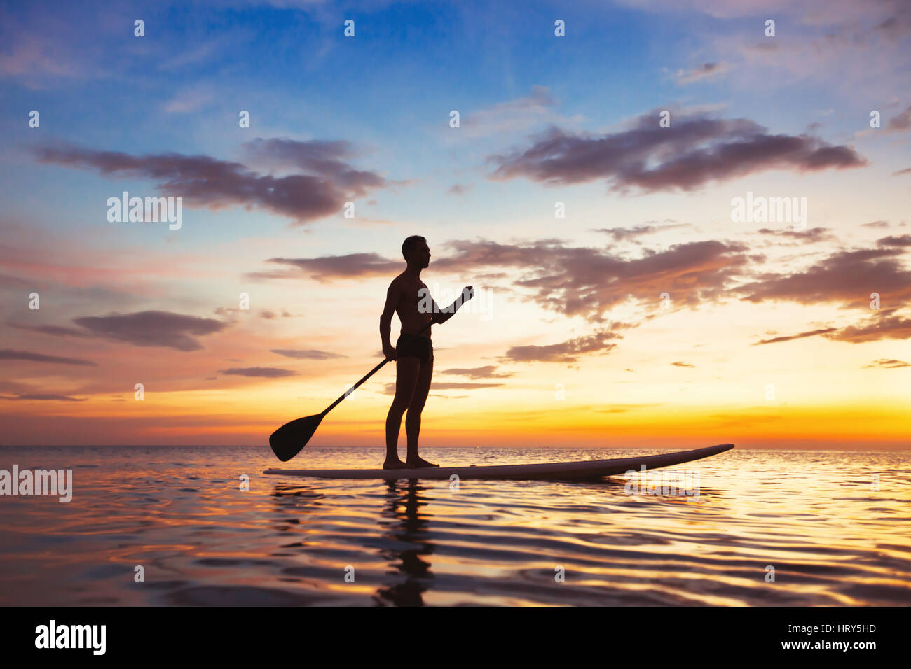 Paddeln Sie stehende Brett, Freizeit-Aktivitäten am Strand, schöne Silhouette des Mannes bei Sonnenuntergang Stockfoto