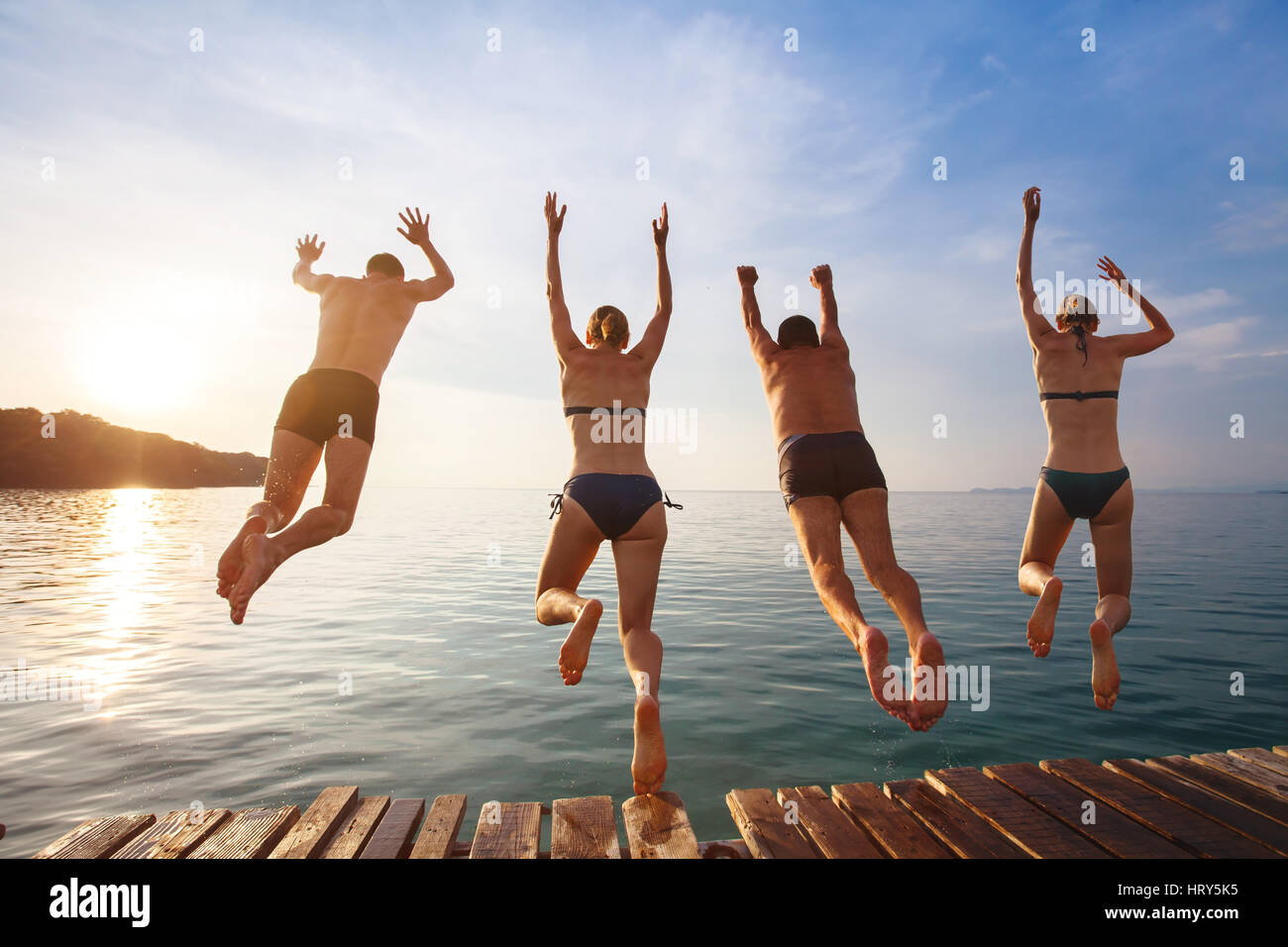 Gruppe von Freunden vom Pier ins Meer springen glücklich Strandurlaub Stockfoto
