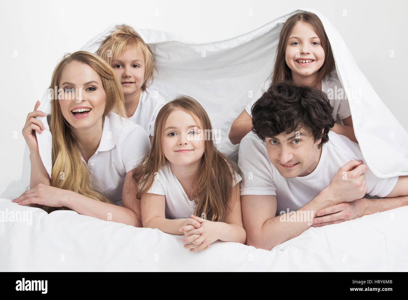 Familie mit drei Kindern im Bett aufwachen lächelnd Stockfoto